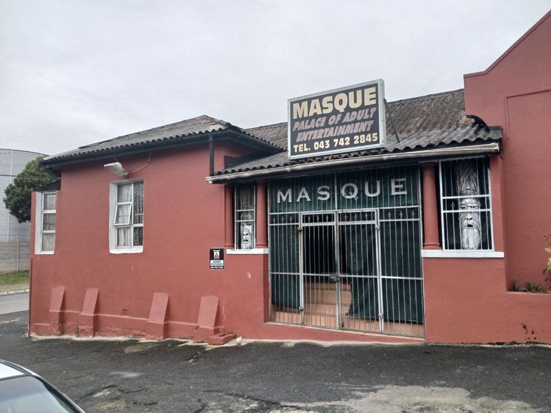 Front facade of a commercial property featuring a security gate, tiled roof, and exterior signage.
