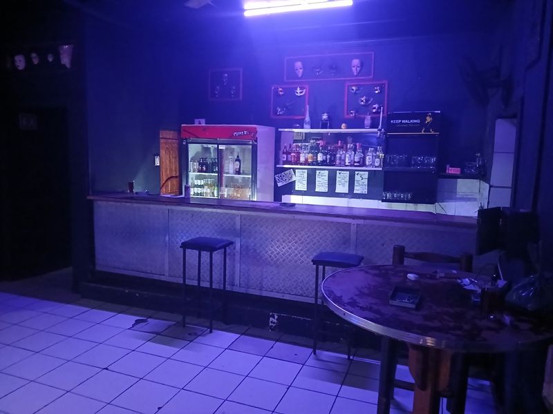 A dedicated bar area featuring a built-in counter, tiled flooring, and ambient lighting, suitable for entertainment or hospitality use.