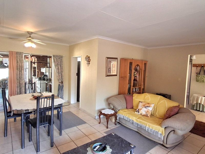 An open-plan living and dining area featuring tiled flooring, a ceiling fan, and sliding glass doors leading to an outdoor space.