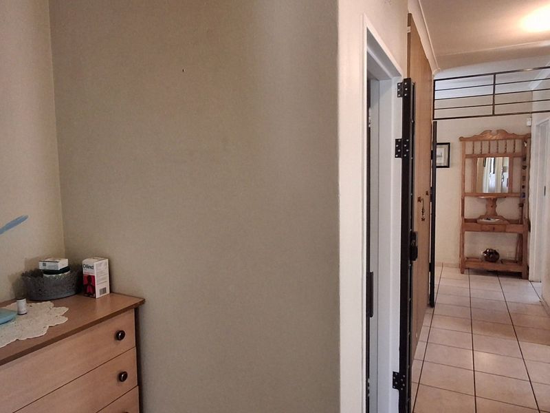 A functional hallway featuring tiled flooring, built-in storage cupboards, and a security gate, providing access to various rooms within the home.