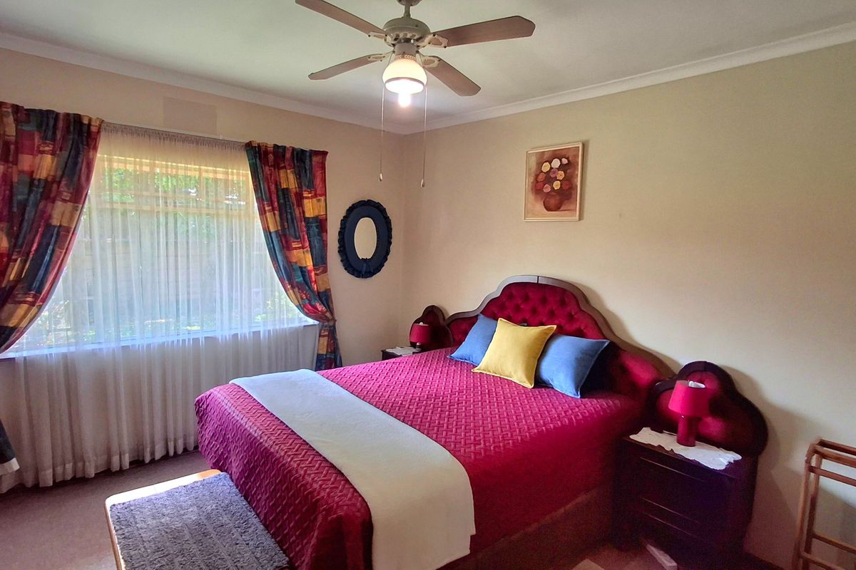 A well-maintained bedroom featuring a ceiling fan and neutral wall finishes, offering a comfortable and functional living space.