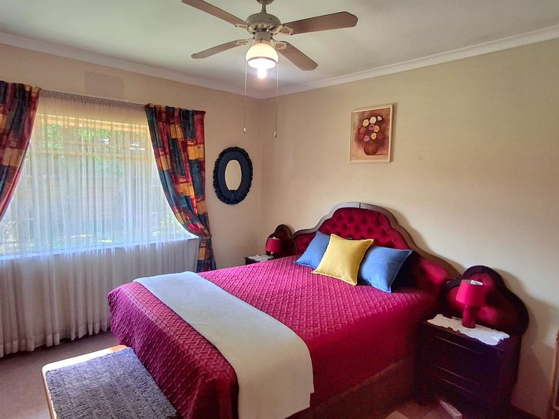 A well-maintained bedroom featuring a ceiling fan and neutral wall finishes, offering a comfortable and functional living space.