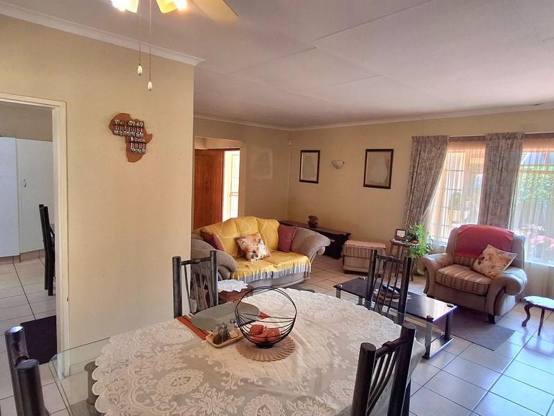 Open plan living and dining area featuring tiled flooring and neutral wall tones, with an adjacent kitchen visible through the doorway.