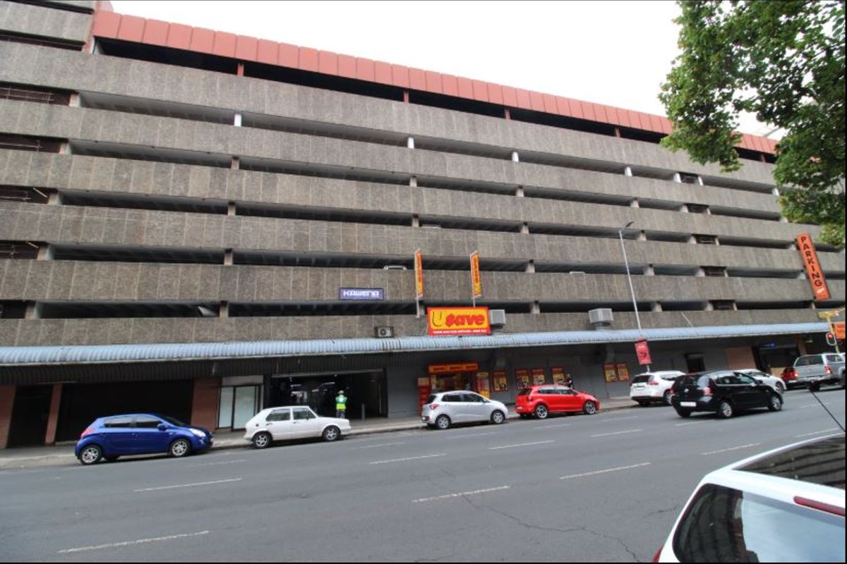 Multi-level commercial parking facility with street-level retail frontage and prominent signage, featuring a concrete facade and integrated parking levels.