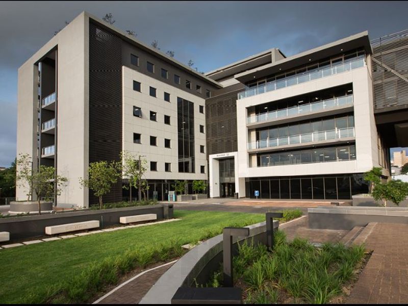 Modern commercial office building featuring a contemporary glass and concrete facade, integrated balconies, and well-maintained landscaped grounds with paved pedestrian walkways.