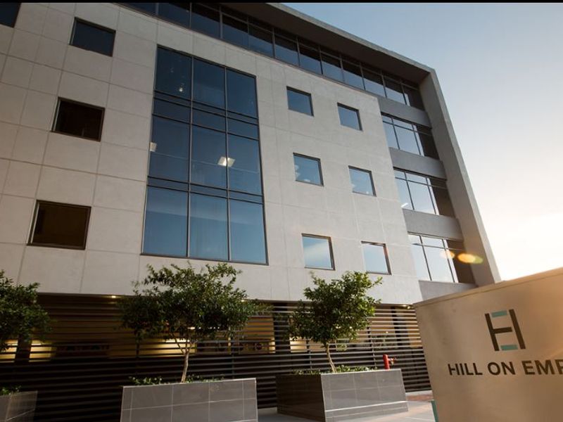 Modern commercial office building facade featuring large glass curtain walls, contemporary cladding, and professional signage at the entrance.