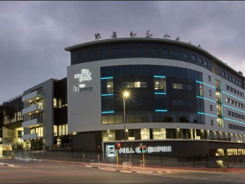 Modern commercial office building facade featuring contemporary glass and concrete architecture with integrated LED lighting and prominent corporate signage.