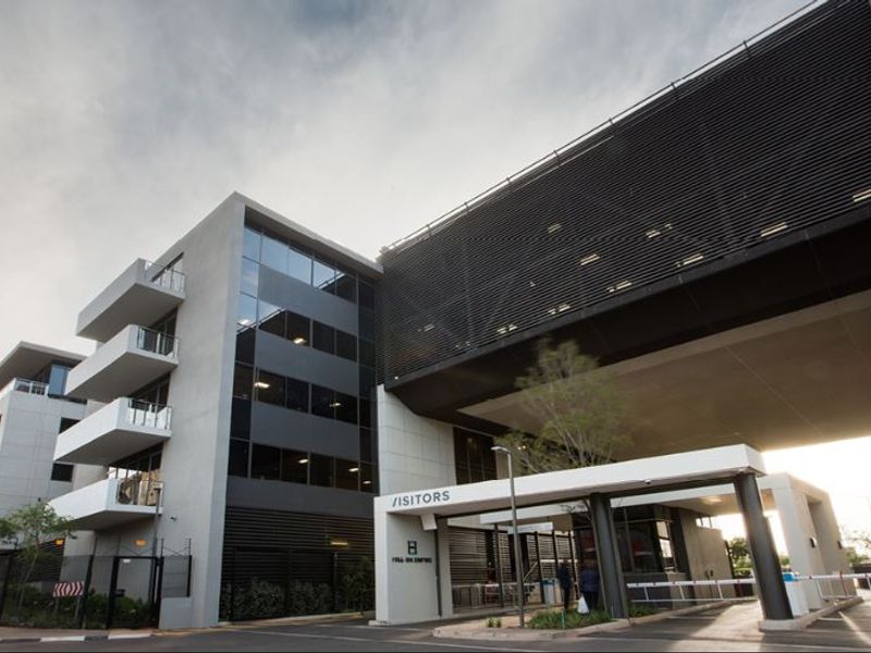 Modern commercial office building exterior featuring a dedicated visitor entrance, secure access control, and contemporary architectural design with multi-level balconies.