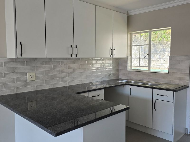 Modern kitchen featuring white cabinetry, dark granite countertops, and a stylish subway tile backsplash, offering a clean and functional workspace.