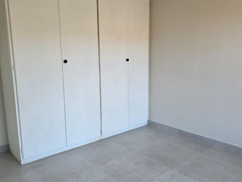 A clean, empty bedroom featuring neutral tiled flooring and functional built-in cupboards, providing a blank canvas for personalization.