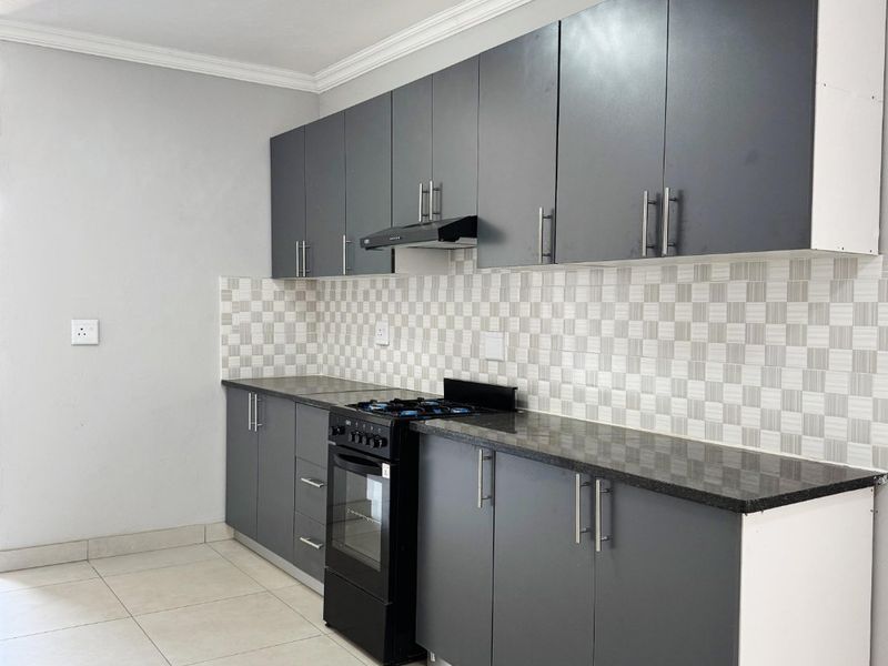 Modern kitchen featuring dark grey cabinetry, granite countertops, a tiled backsplash, and a built-in stove with an extractor fan.