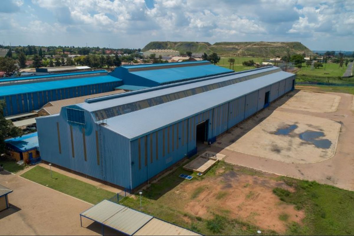 Aerial view of a large industrial warehouse facility featuring extensive metal roofing and a spacious paved yard area.