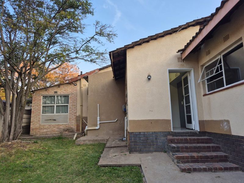 Rear exterior view of the property featuring brick steps, exposed plumbing, and a combination of brick and plastered wall finishes.