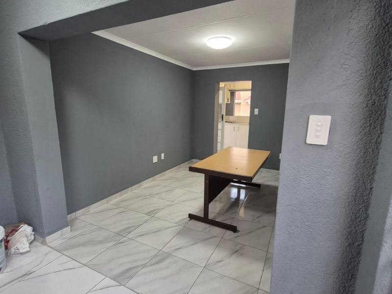 Open plan living area featuring modern marble-look floor tiles, neutral grey walls, and direct access to the kitchen area.