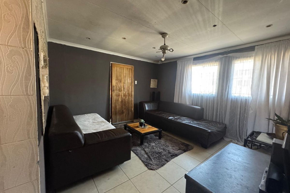 A living room featuring tiled flooring, recessed lighting, and a ceiling fan, requiring cosmetic updates to the walls and ceiling finishes.