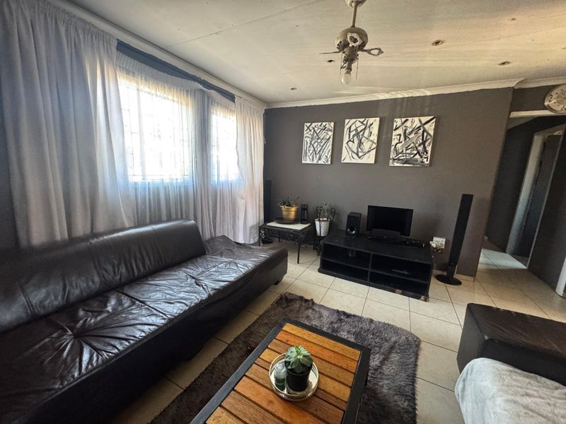 A living room featuring tiled flooring, recessed lighting, and a ceiling fan, currently showing signs of wear on the ceiling surface.