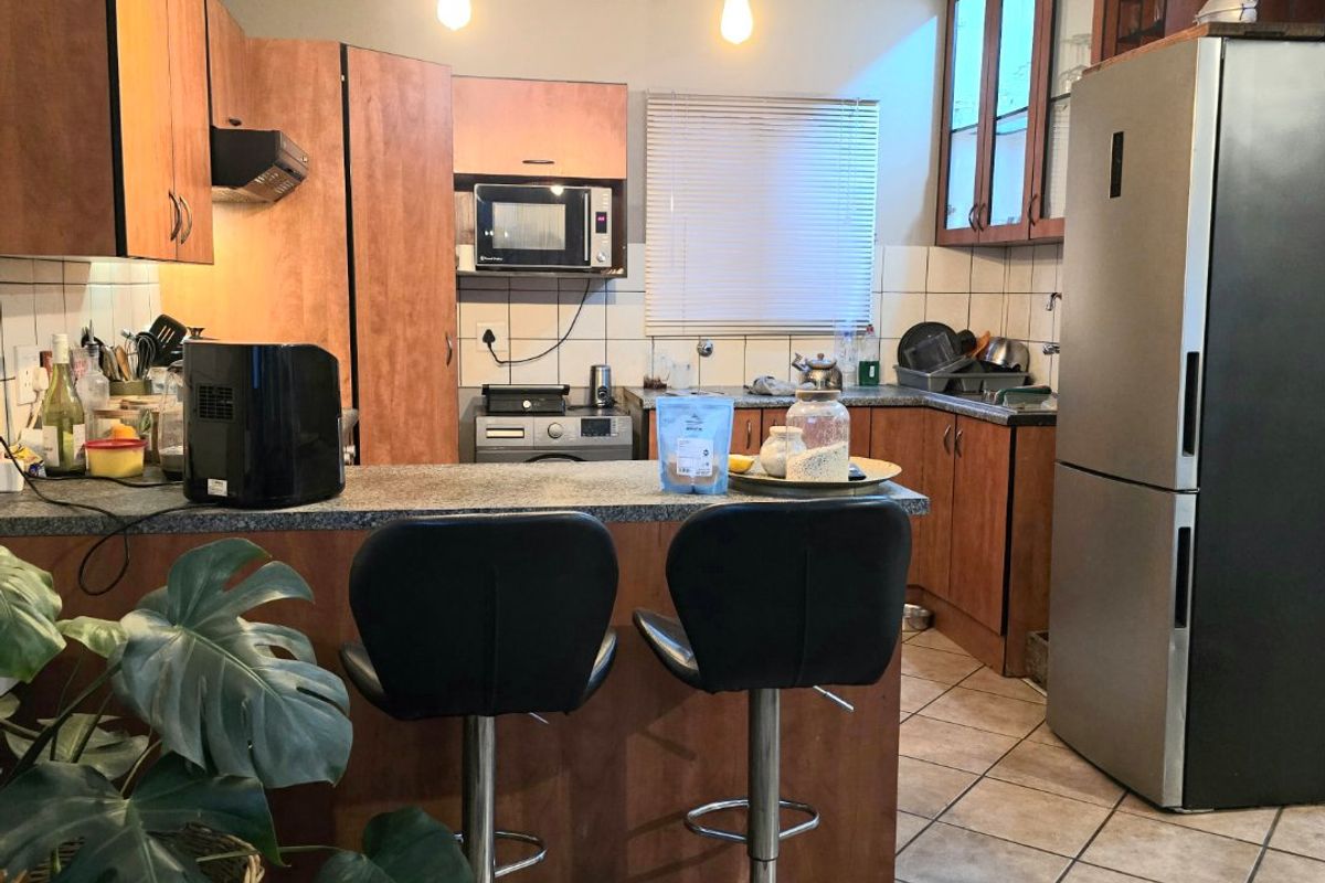 A functional kitchen featuring wood-tone cabinetry, granite countertops, a breakfast bar, and tiled flooring, offering a practical layout for daily meal preparation.