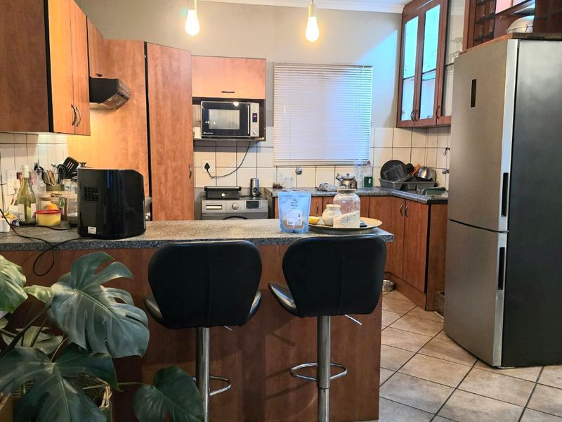 A functional kitchen featuring wood-tone cabinetry, granite countertops, a breakfast bar, and tiled flooring, offering a practical layout for daily meal preparation.