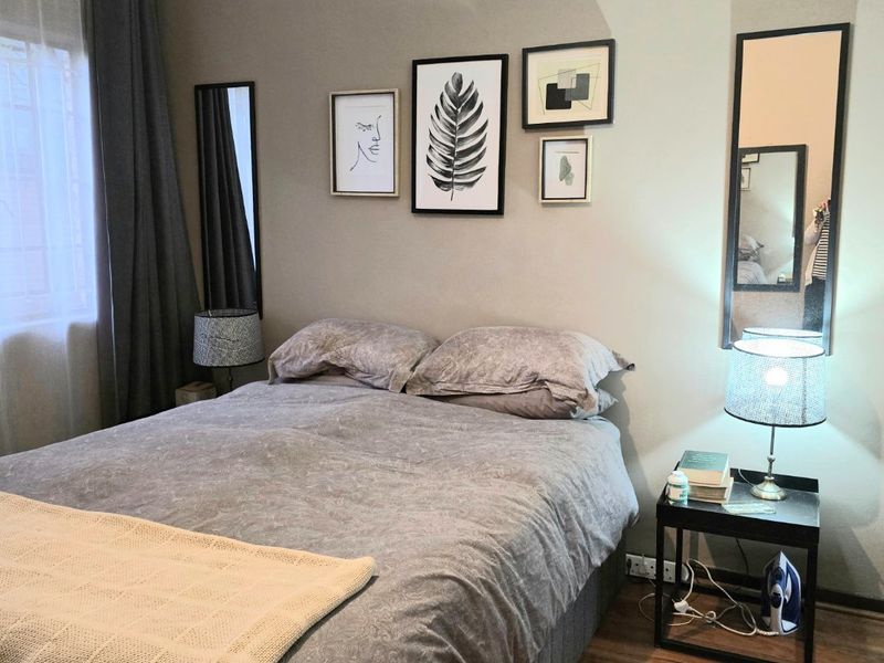 A cozy bedroom featuring laminate flooring and neutral wall tones, providing a comfortable and well-maintained sleeping space.