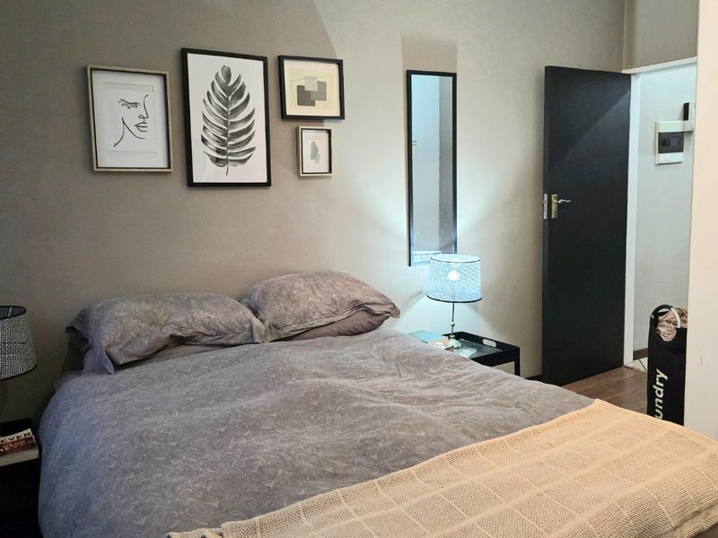 A cozy bedroom featuring laminate flooring and neutral wall tones, providing a comfortable and functional sleeping space.