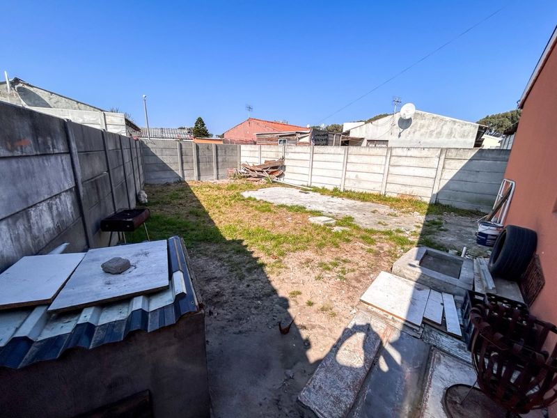 A rear outdoor area featuring a precast concrete boundary wall and a concrete slab, offering potential for landscaping and garden development.