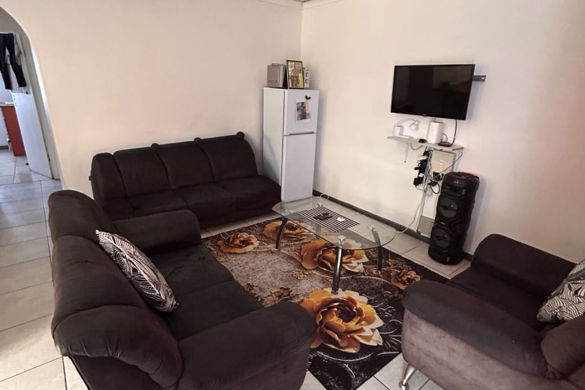 A living room featuring tiled flooring and a textured ceiling, with an open archway leading to adjacent areas.