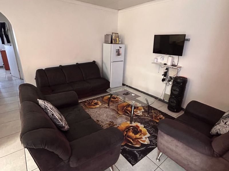 A living room featuring tiled flooring and a textured ceiling, with an open archway leading to adjacent areas.