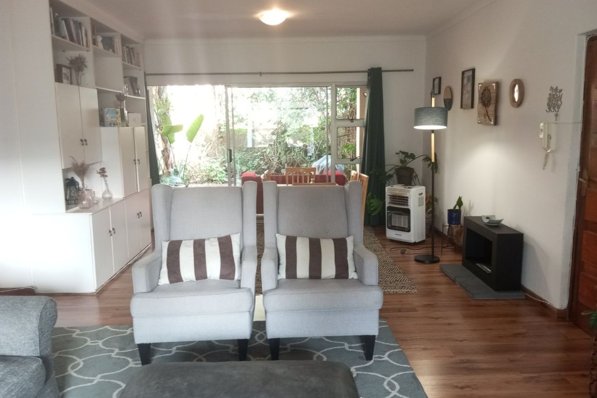 A living room featuring laminate flooring, a built-in shelving unit, and a sliding glass door providing access to the outdoor area.