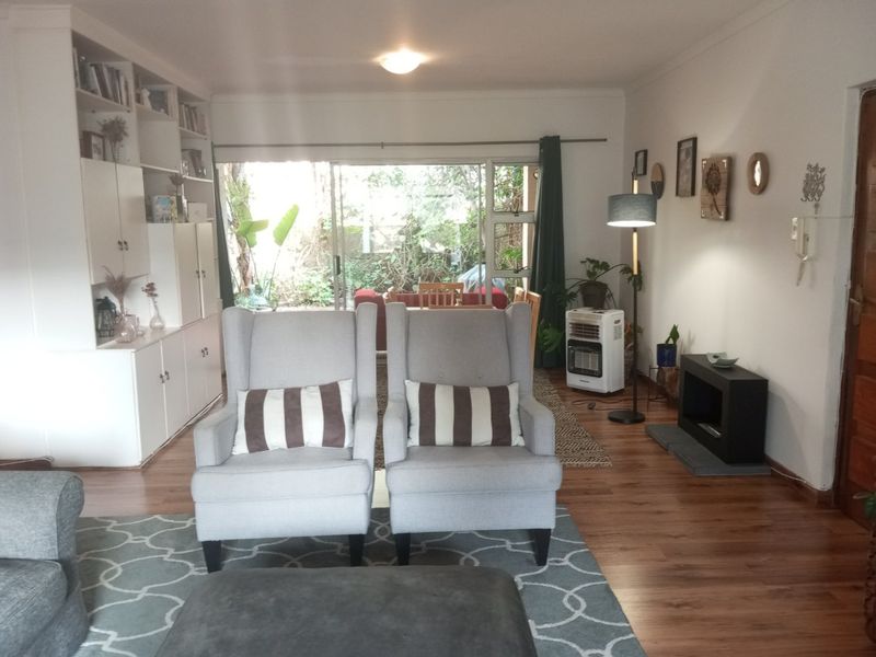 A living room featuring laminate flooring, a built-in shelving unit, and a sliding glass door providing access to the outdoor area.