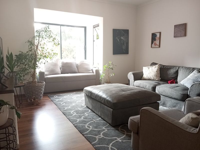 A comfortable living room featuring laminate flooring and a large sliding glass door that provides natural light.