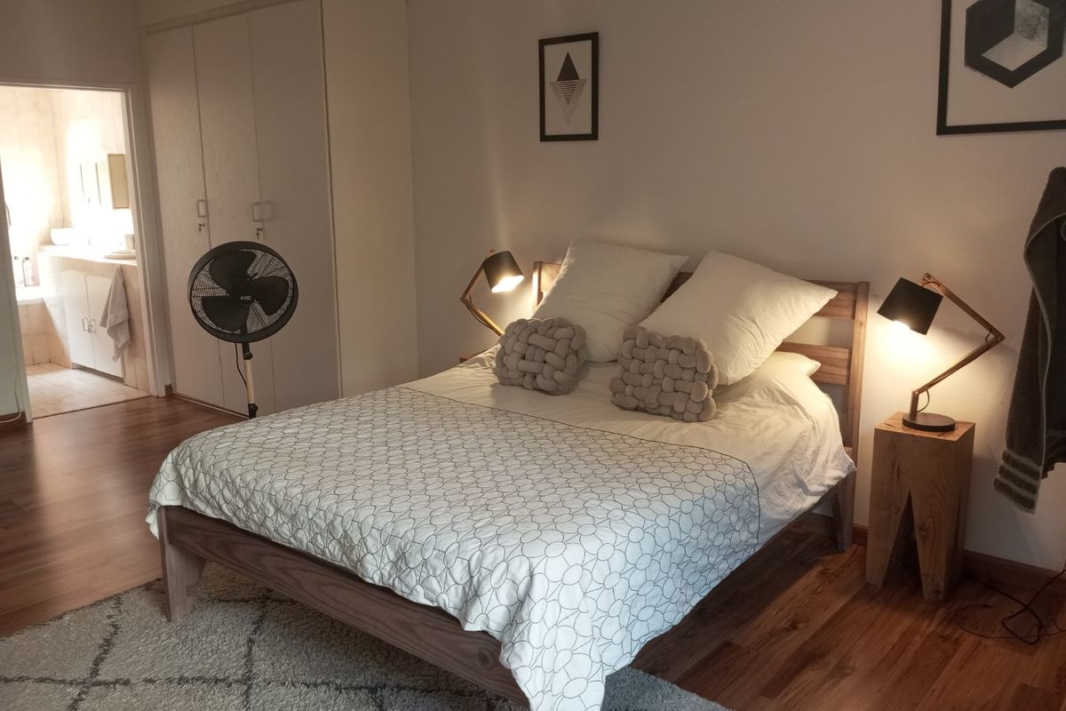 A well-maintained bedroom featuring laminate flooring, built-in cupboards, and direct access to an en-suite bathroom.