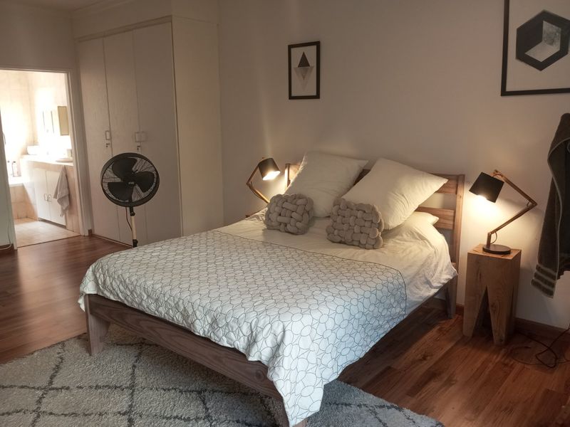 A well-maintained bedroom featuring laminate flooring, built-in cupboards, and direct access to an en-suite bathroom.