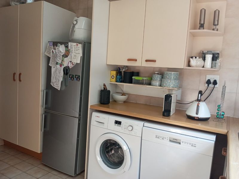 A functional kitchen area featuring built-in cabinetry, laminate countertops, tiled backsplash, and integrated laundry and dishwasher appliances.
