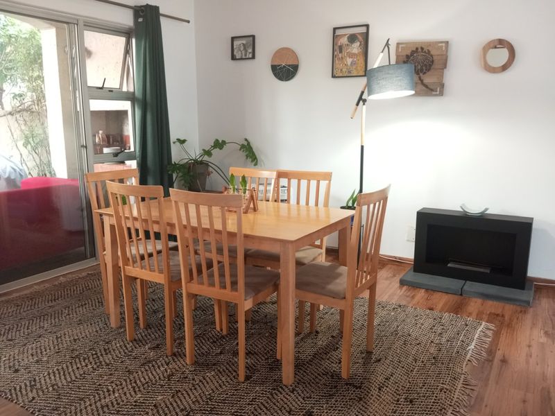 Dining area featuring laminate flooring, a built-in fireplace, and a sliding glass door providing access to the outdoor space.