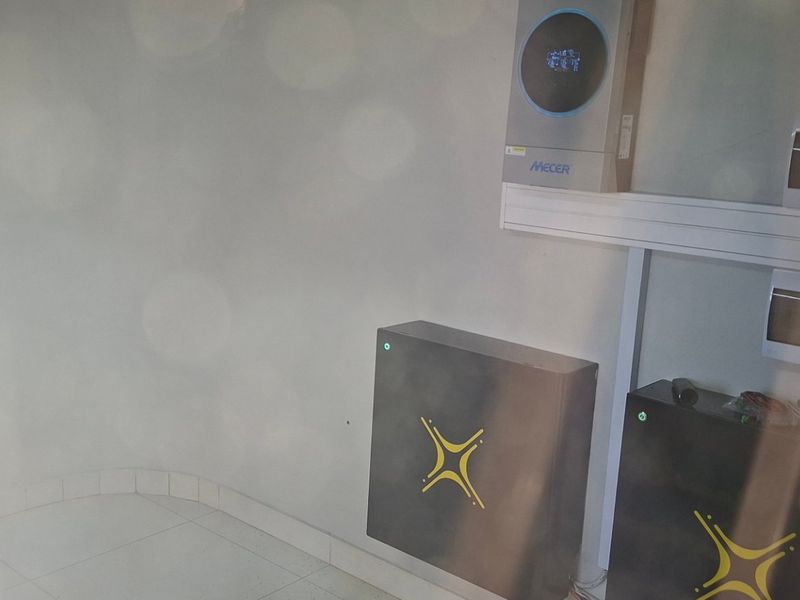 A utility space featuring a wall-mounted inverter system and battery storage units, providing essential power backup infrastructure.
