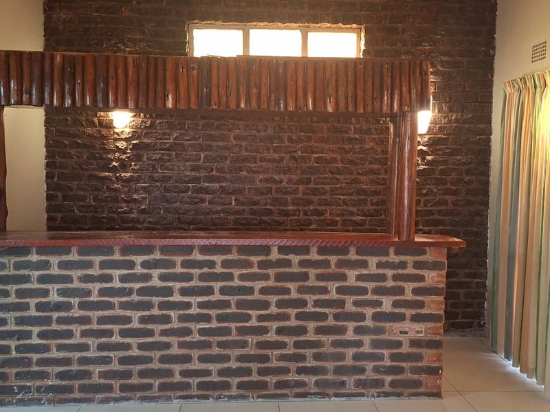 A dedicated bar area featuring a built-in brick counter, exposed brick feature wall, and timber canopy, providing a rustic entertainment space.