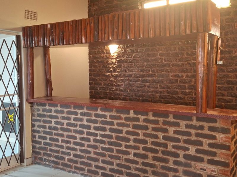 A dedicated bar area featuring a built-in brick counter, timber canopy, and rustic exposed brick wall finishes.