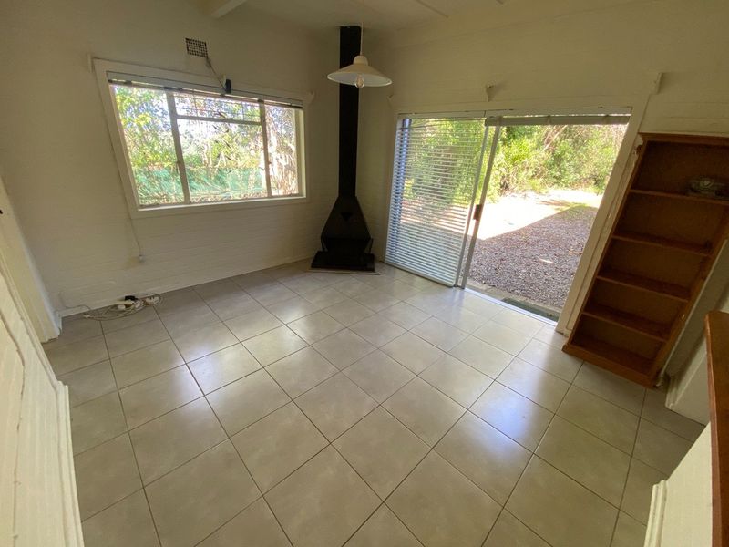 An empty living room featuring tiled flooring, a freestanding fireplace, and large sliding glass doors providing access to the outdoor area.