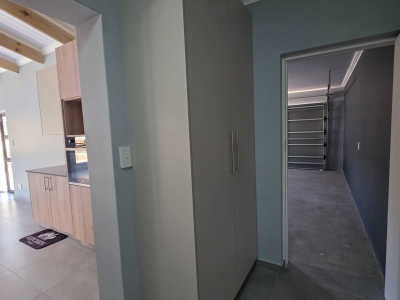 A functional utility area featuring built-in cabinetry and exposed timber ceiling beams, providing direct access to the adjacent kitchen and garage space.