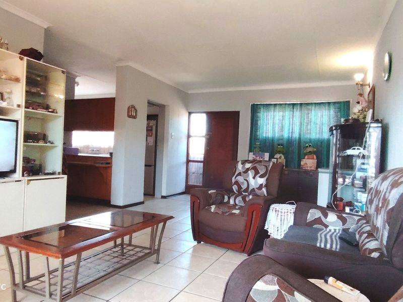 Open-plan living area featuring tiled flooring and a view into the adjacent kitchen space with built-in cabinetry.