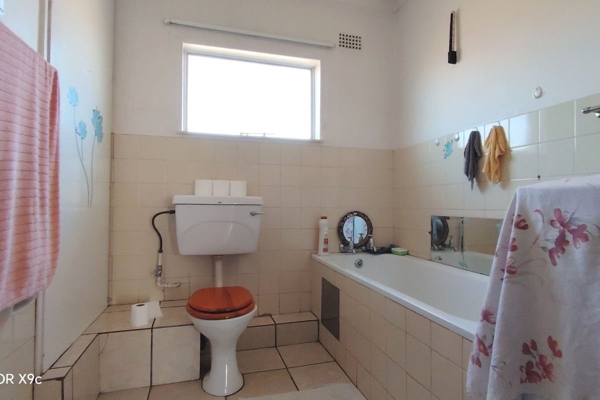 A dated bathroom featuring a standard bathtub, toilet, and tiled finishes, offering potential for modernization and renovation.
