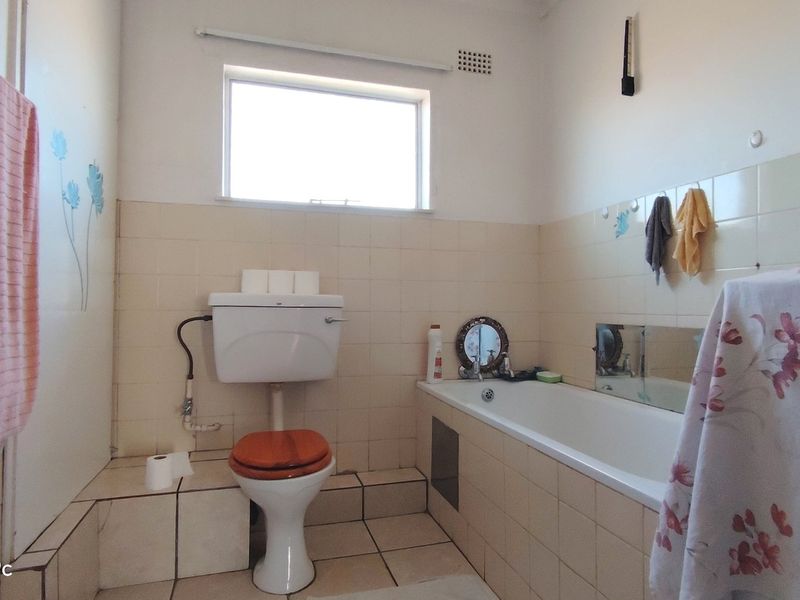 A dated bathroom featuring a standard bathtub, toilet, and tiled finishes, offering potential for modernization and renovation.