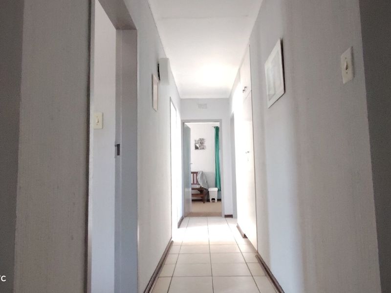 A functional hallway featuring tiled flooring and built-in storage cupboards, providing access to various rooms within the apartment.