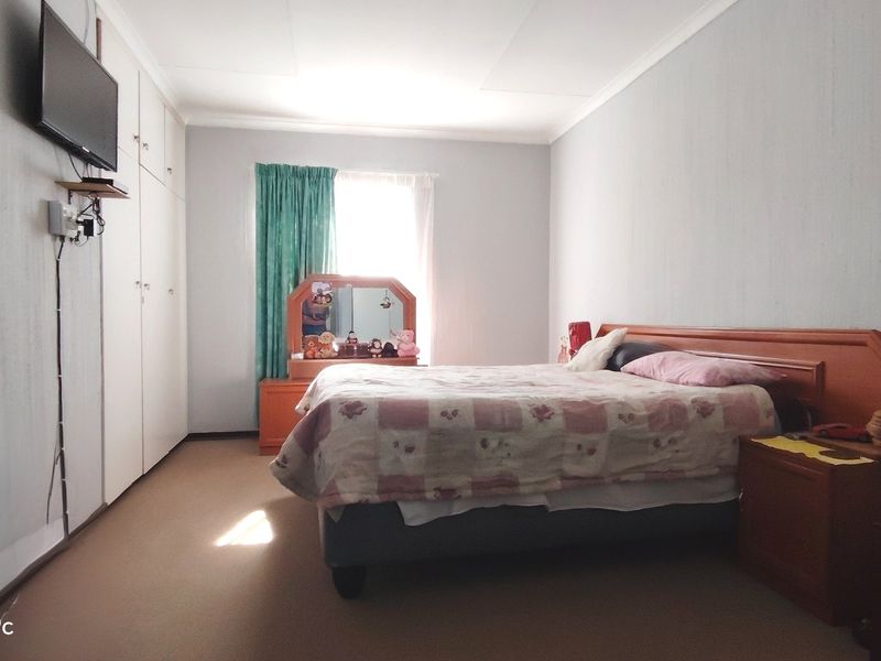 A bedroom featuring built-in cupboards, carpeted flooring, and a coved ceiling, providing a functional space with potential for modernization.
