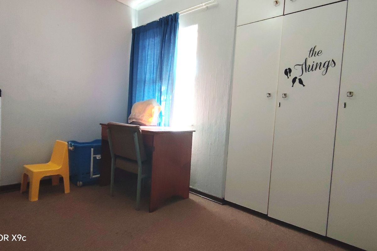 A bedroom featuring built-in cupboards and carpeted flooring, offering a functional space with natural light.