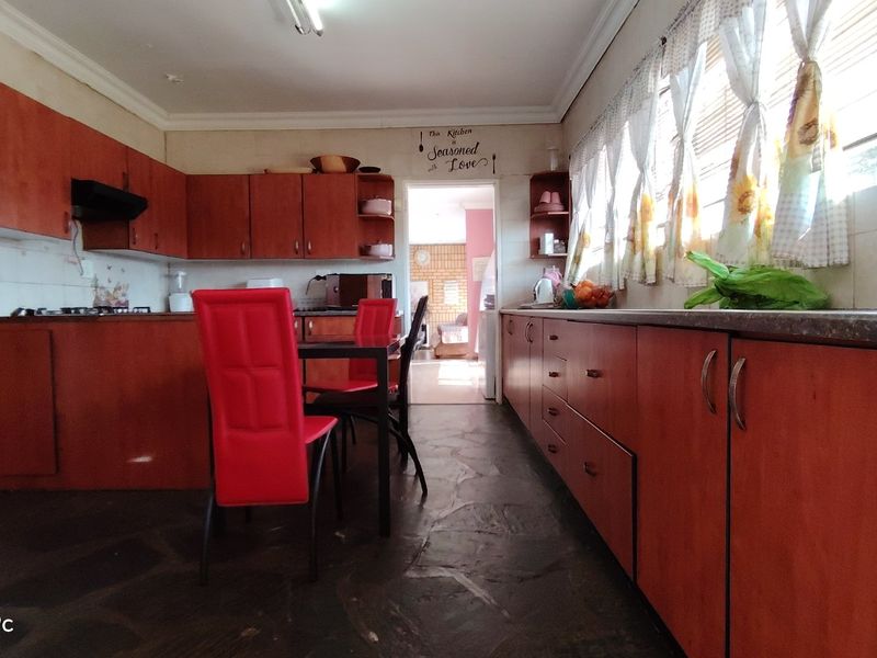 A functional kitchen featuring extensive built-in cabinetry, stone flooring, and a tiled splashback, offering a traditional layout with ample storage space.