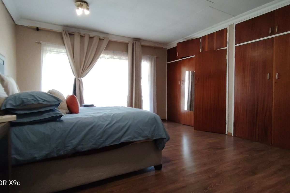 Spacious bedroom featuring extensive built-in wooden cabinetry and laminate flooring, offering ample storage and a neutral aesthetic.