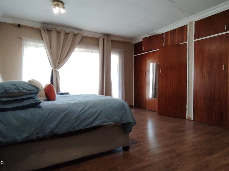 Spacious bedroom featuring extensive built-in wooden cabinetry and laminate flooring, offering ample storage and a neutral aesthetic.