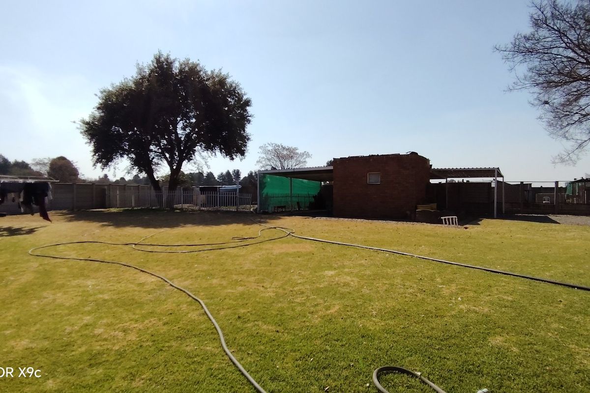 A spacious rear garden area featuring a brick outbuilding with a covered patio and perimeter precast concrete walling.