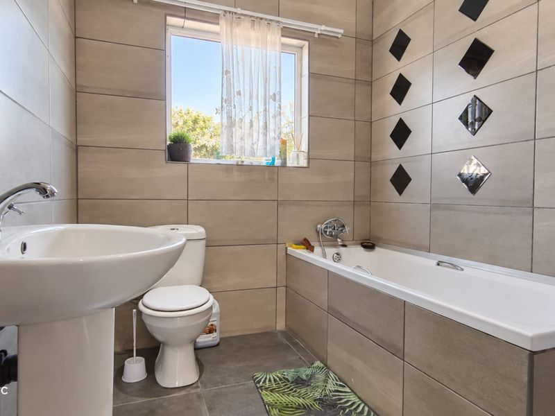 A functional bathroom featuring a pedestal basin, toilet, and a built-in bathtub with tiled wall finishes and flooring.